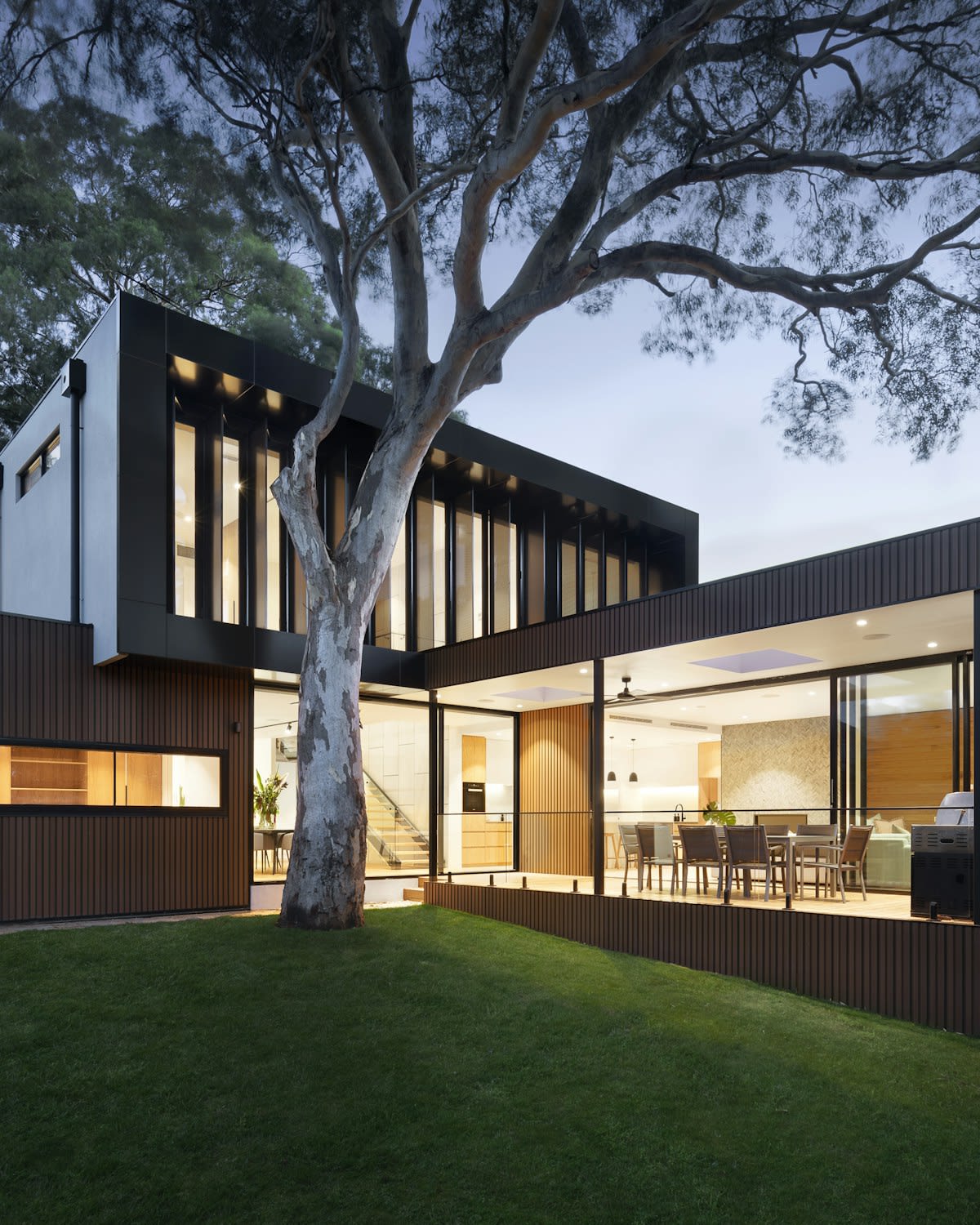 Modern two-storey house at dusk with lit windows
