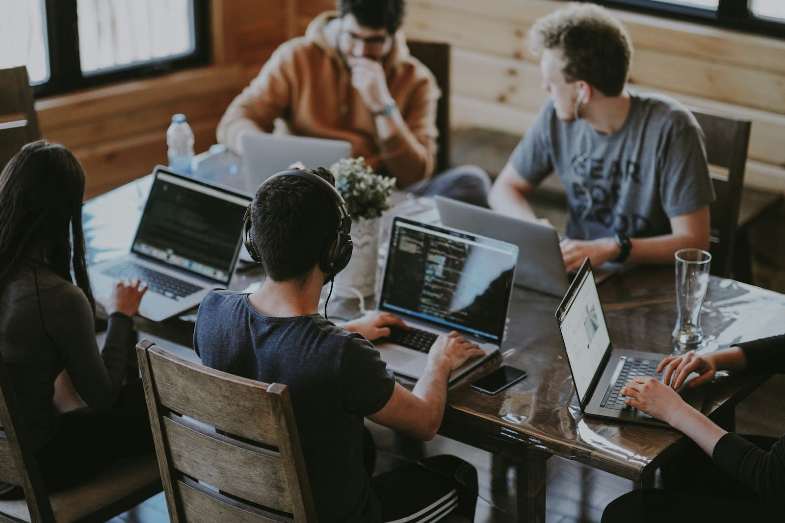 A small team working on laptops around a wooden table